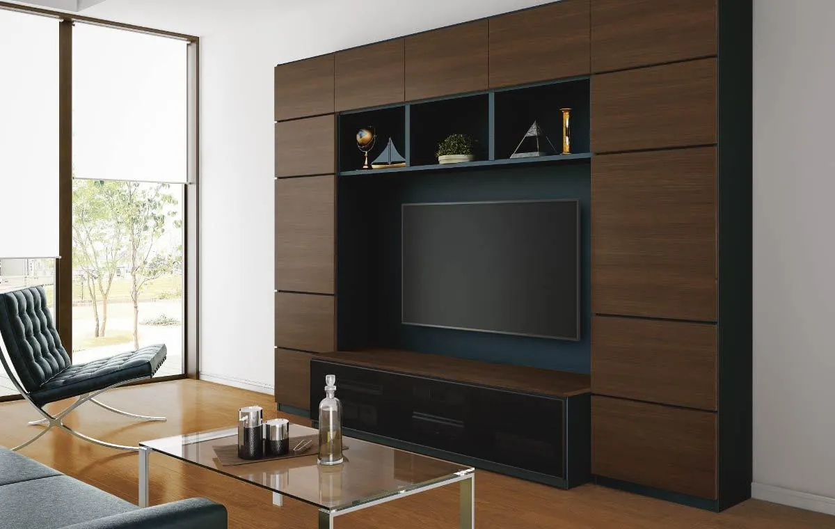 大建工業「MiSEL(ミセル)」のivingハイタイプのオーダーテレビ台/TVボード壁面収納の画像。開放感ある邸の広くモダンなlivingの真ん中に、ダークブラウンの木目の戸棚、飾り棚、天ぶくろが一体になったハイタイプオーダーテレビボード壁面収納が施工されている。壁面収納は奥行きが抑えられ、圧迫感が少ない仕様。中央には壁掛けテレビがあり、まわりにはレザーのソファやカウチソファが置かれている。ソファの前にはガラスのテーブルがあり、テーブルの上には食器が置かれている。