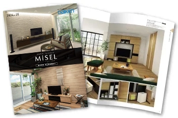 大建工業「MiSEL」のカタログ表紙画像。画像には木目フローリングを使用したリビングが写っており、右側の白が美しいテレビ壁面収納は、テレビボード、本棚・飾り棚、天袋が一体になったハイタイプ。壁面収納の引出しの扉はホワイトアッシュの木目で、取っ手なしのタイプ。大きな窓から日ざしが差し込む明るい室内には、窓側奥にロータイプのオープン棚、画像の左にはラグが敷かれ、ソファやサイドテーブルがある。手前にはgreenのスツールが置かれている。マリメッコのクッションや天然木のサイドテーブルなど北欧テイストでまとめられている部屋。