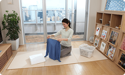畳の上で洗濯物をたたむ女性